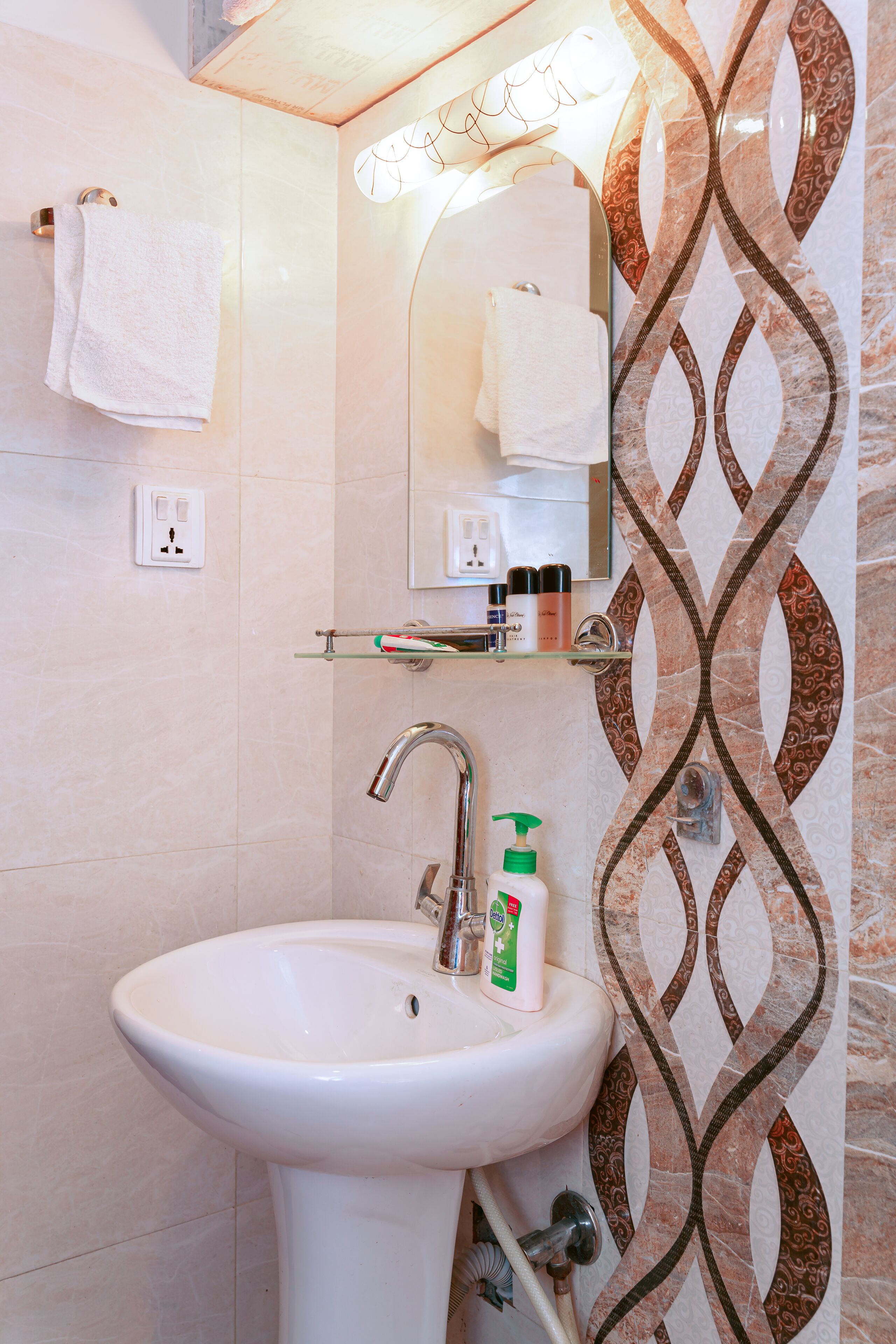 Ein Badezimmer mit einem weißen Waschbecken, einem Spiegel und einer Wand mit Muster.