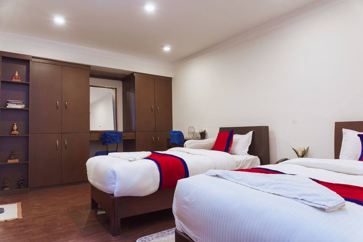 A hotel room with two beds, a wardrobe, and a mirror.