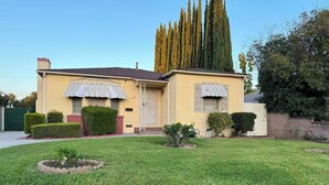 Une maison à deux étages avec une pelouse bien entretenue, un grand arbre et une cheminée en briques.