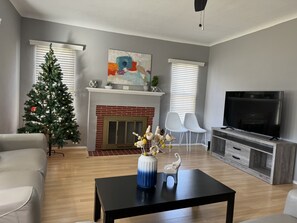 A living room with a fireplace, a television, and a Christmas tree.