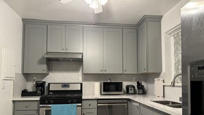 Une cuisine moderne avec des meubles gris, des appareils en acier inoxydable et un ventilateur de plafond.