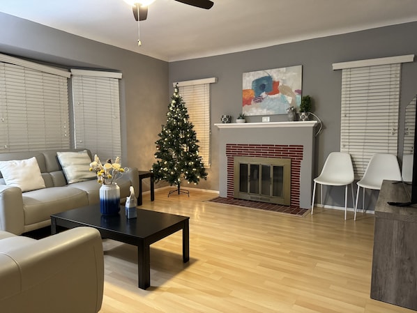 A living room with a fireplace, a Christmas tree, and a sofa.