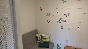 A cozy room with a grey sofa, a green cushion, and two round stools. - FeWo Schneeglocke The cozy little room! (Altenau)