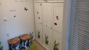 A room with a white wardrobe, a green carpet, and decorative wall stickers. - FeWo Schneeglocke The cozy little room! (Altenau)