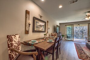 A dining area with a wooden table, chairs, and a view of the outdoors through large windows. - Rio Rancho Guadalupe Rg 206 3 Bedroom Condo by RedAwning (New Braunfels)