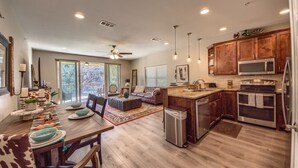 Eine moderne Küche mit Holzausstattung, Edelstahlgeräten und einem Essbereich mit großem Tisch und Stühlen.