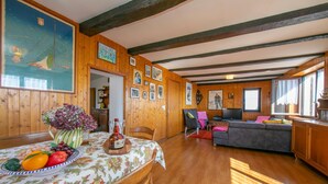 Un intérieur en bois avec une table à manger dressée, ornée de fruits, un canapé et un téléviseur.