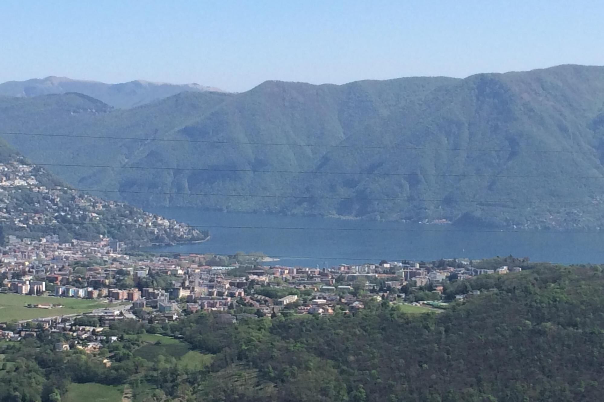 Eine Küstenstadt mit einer dichten Bebauung, einem großen Gewässer und Bergen im Hintergrund.
