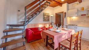 Un comedor con una escalera de madera, un sofá rojo y una mesa lista para dos.