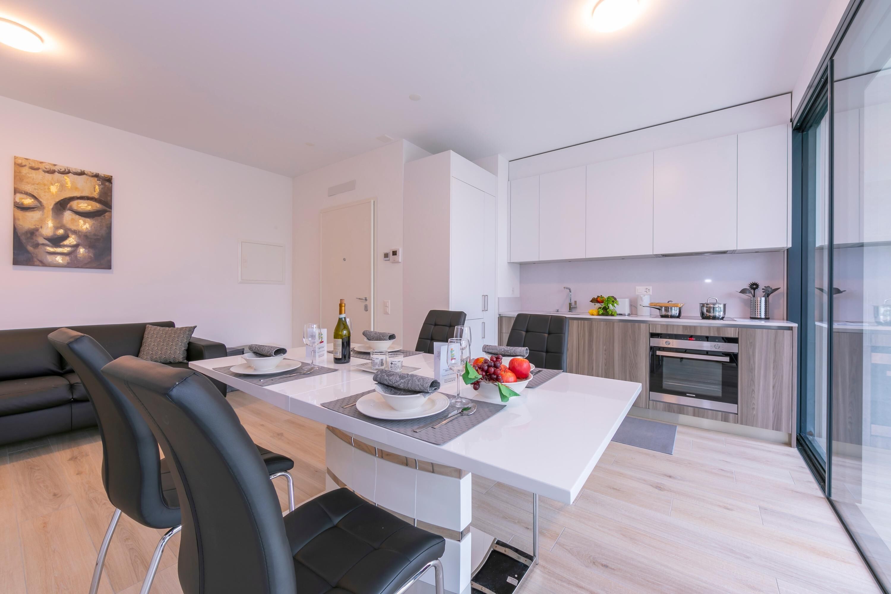 A modern apartment with a dining area, kitchen, and living space.