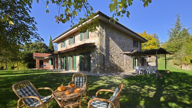 Une maison en pierre dotée d’un patio aménagé avec des chaises en osier et une table sur laquelle sont disposées des théières.