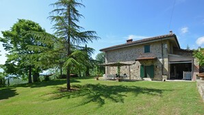 Une maison en pierre avec un patio couvert et un garage.