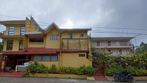 A two-story yellow building with a red roof, a balcony, and a sign indicating an entrance. - OYO 909 Jc Affordable Transient (Tagaytay)
