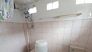 A bathroom with a toilet, a sink, a shower, and a large white storage barrel. - OYO 909 Jc Affordable Transient (Tagaytay)