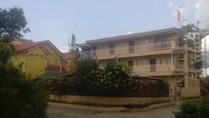 A multi-story building with balconies, surrounded by greenery and a clear sky. - OYO 909 Jc Affordable Transient (Tagaytay)
