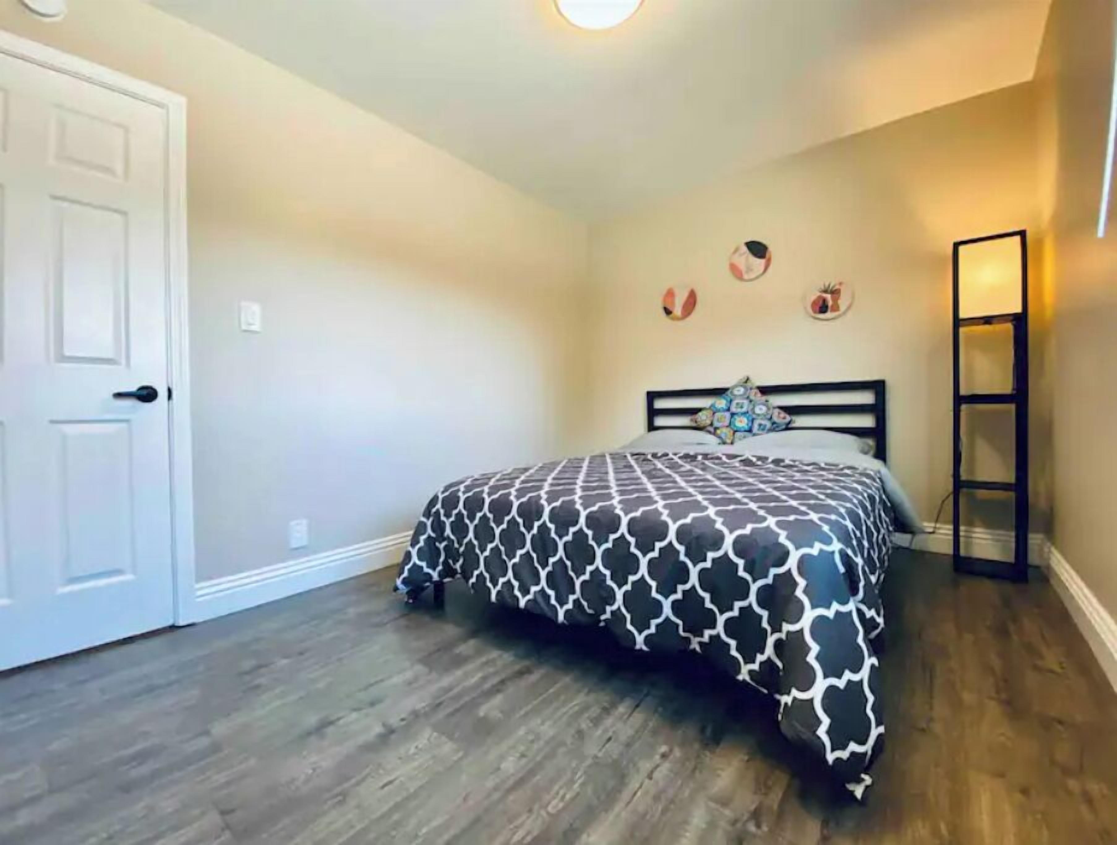 Un dormitorio con cama, puerta y estante en la pared.