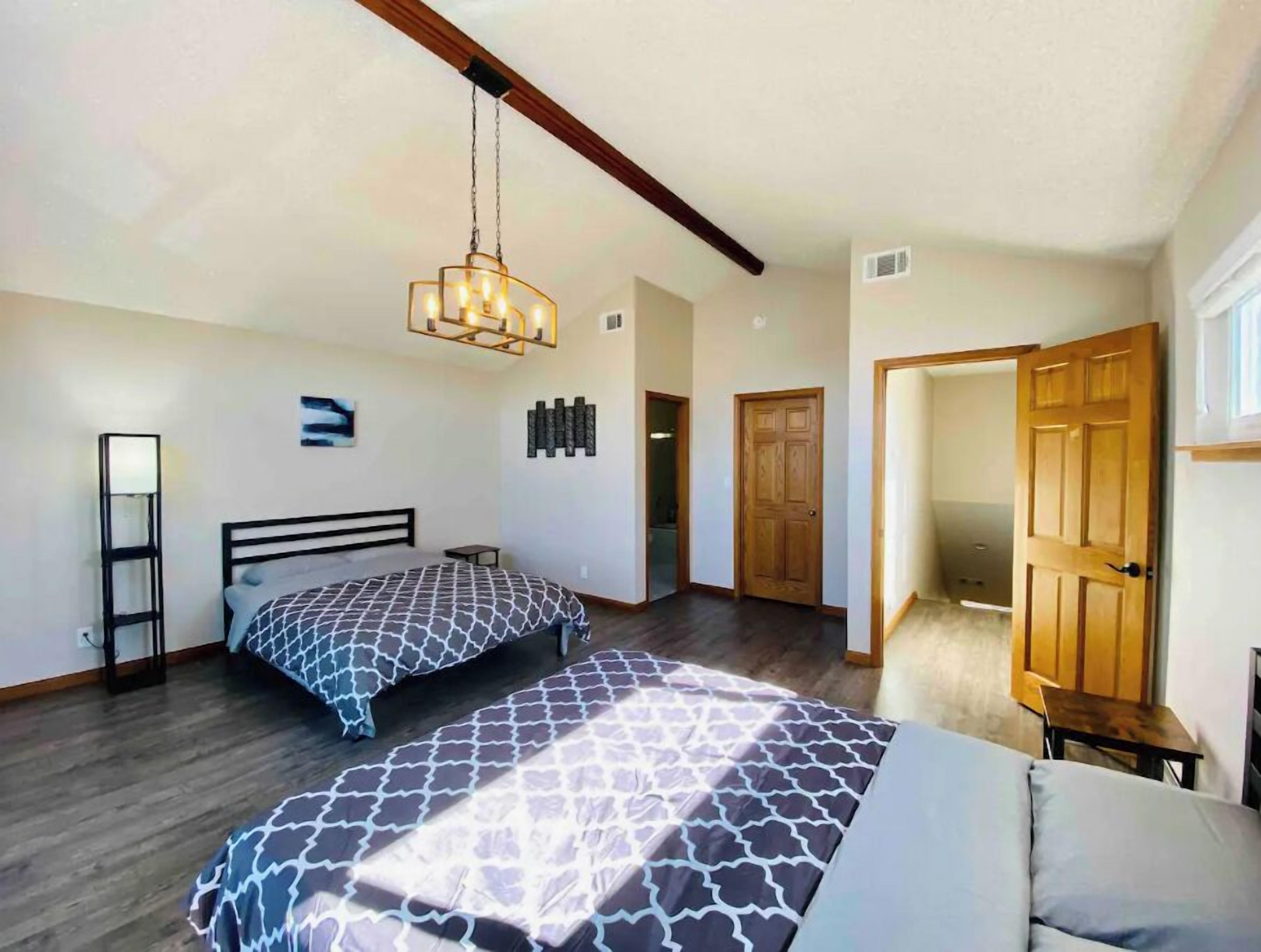 A bedroom with a large bed, a hanging light fixture, and a wooden door.