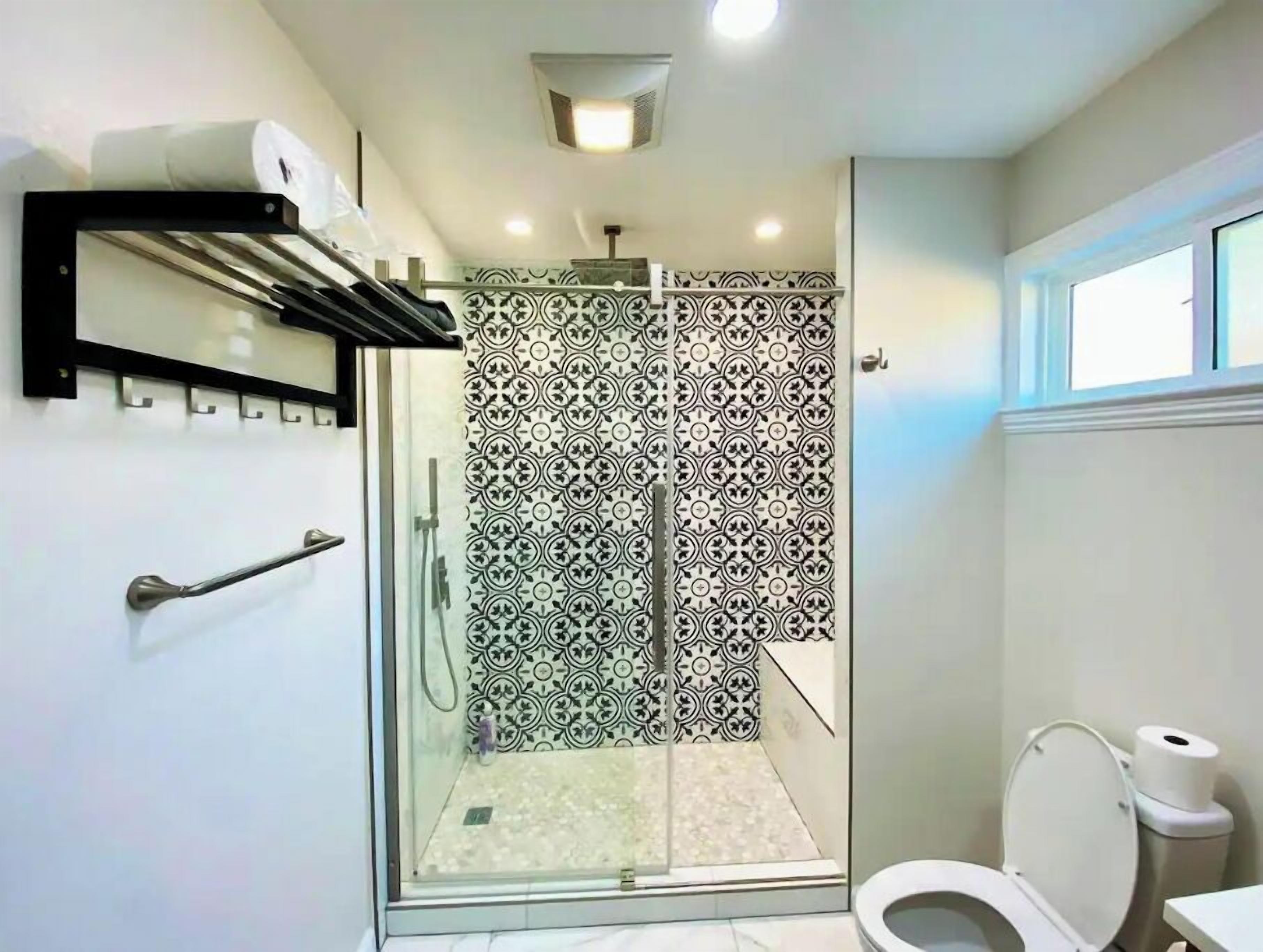 A modern bathroom with a shower, toilet, and a towel rack.