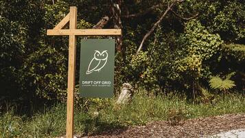 Une enseigne pour « Drift Off Grid Luxury Eco Glamping », avec un poteau en bois et un panneau vert.