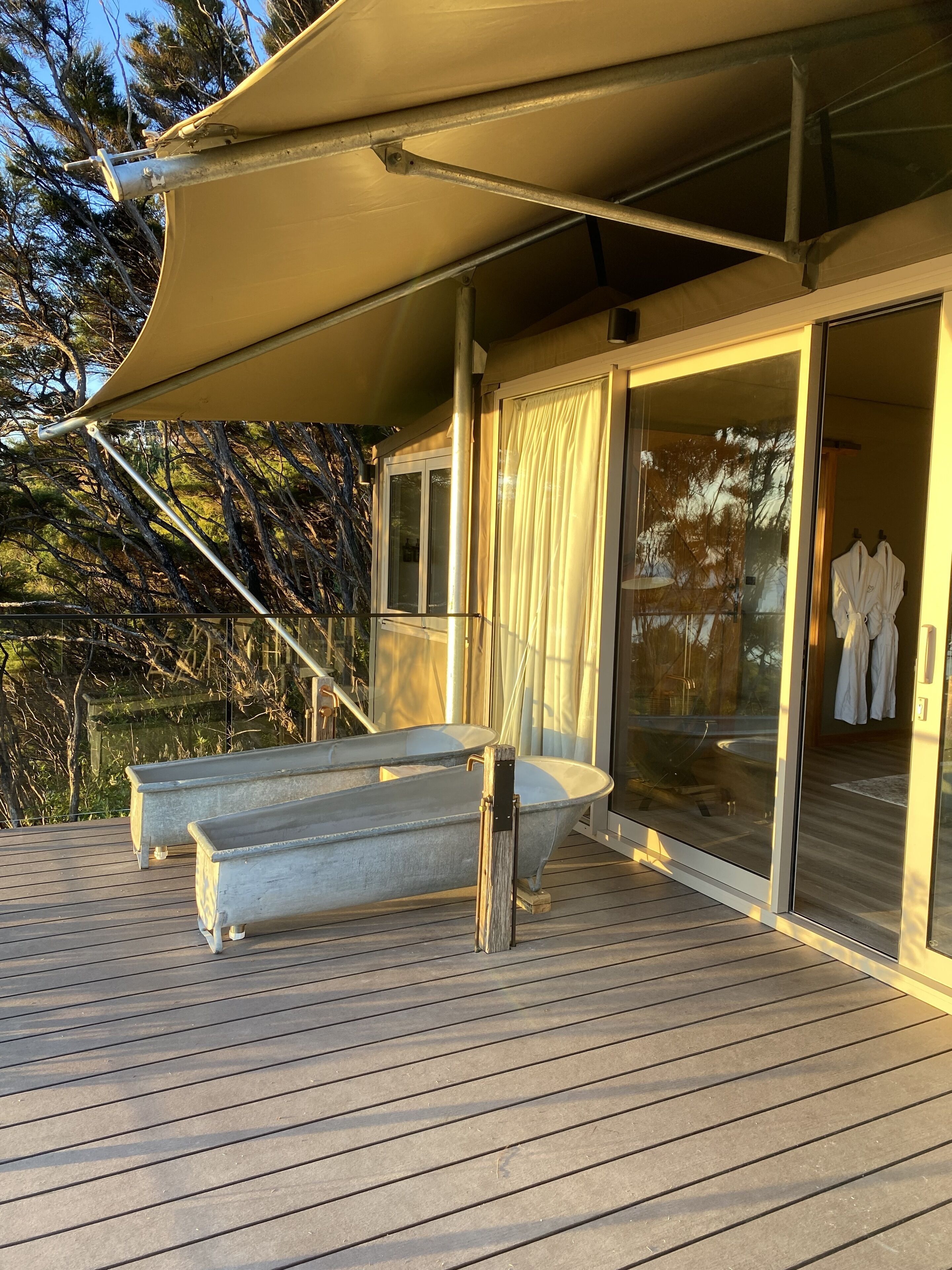 A wooden deck with a large bathtub and a canopy.