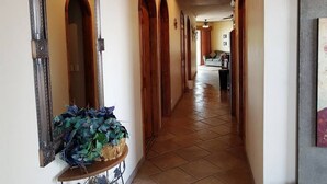 Un couloir avec des portes en bois et un sol carrelé, qui mène à une pièce contenant un canapé et une table basse.