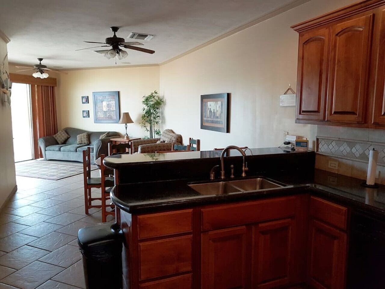 A kitchen with wooden cabinets, a black countertop, and a ceiling fan.