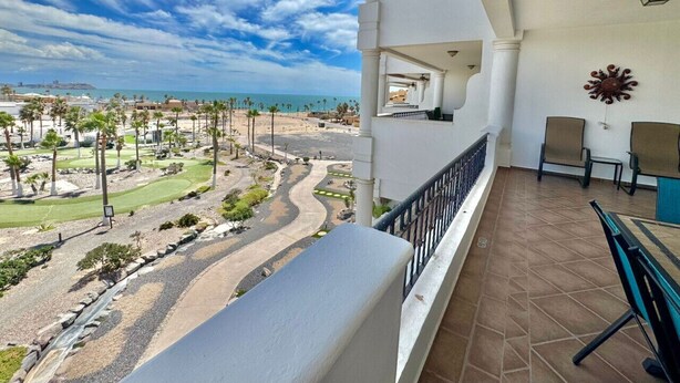 Een balkon met uitzicht op een golfbaan en strand.