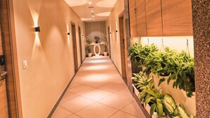Um corredor com chão de azulejos, armários de madeira e plantas em vasos.