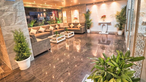 Um lobby moderno com sofás, mesa de centro e plantas em vasos.