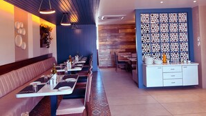 Um restaurante com um balcão comprido, cabines e uma parede decorativa.