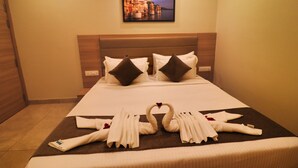 Quarto de hotel com cama arrumada, almofadas e arranjo de toalha em forma de cisne decorativo.