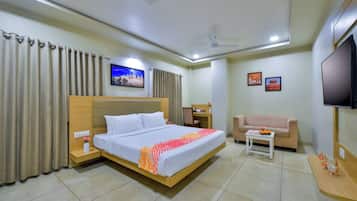 A hotel room with a bed, a desk, a sofa, a TV, and curtains.