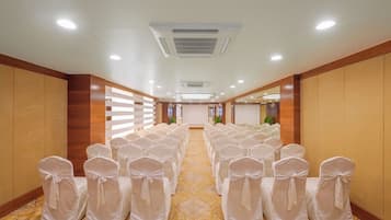 Ein Hotelkonferenzraum mit Reihen von Stühlen, einer Projektionsleinwand und einem Teppichboden.