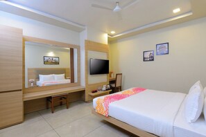A hotel room with a bed, a desk, a chair, a television, and a mirror. - Ginger Udaipur Hiran Magri (Udaipur)