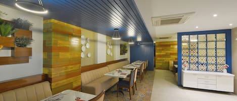 Un restaurante con una barra larga, mesas en cabinas y un suelo estampado.