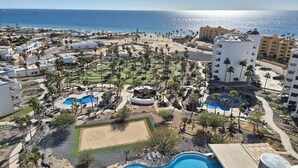 A resort with multiple swimming pools, palm trees, and beachfront views.