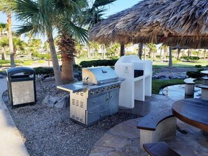 Un espace barbecue extérieur comprenant un gril, une poubelle et un coin salon.
