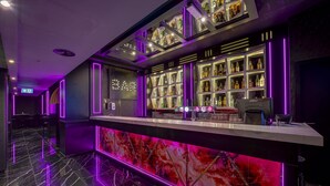 Eine Bar mit einer Marmorplatte, Flaschenregalen und Neonbeleuchtung.