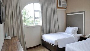 Una habitación de hotel con una cama, mesita de noche y una ventana con cortinas.
