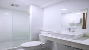 Un baño moderno con cabina de ducha de vidrio, inodoro blanco y tocador con lavabo y espejo.