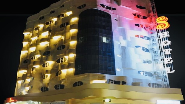 Un hotel de varios pisos, con ventanas iluminadas y un letrero visible en la fachada.