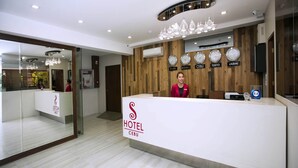 Un mostrador de recepción de hotel con diseño moderno, un reloj que marca la hora y un cartel que indica que el hotel se encuentra en Cebú.