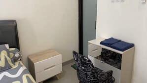 Une chambre à coucher comprenant un lit, une table de chevet, une commode, une chaise et un miroir.