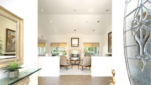 A spacious room with a fireplace, a dining area, and a view of the outdoors. - Spanish Mission in Gated Private Golf Club (Palm Desert)