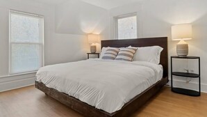 A bedroom with a large bed, two bedside tables, and a ceiling light fixture.