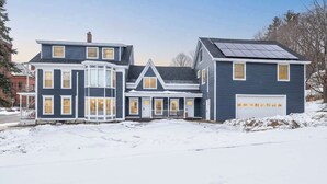 Una casa de dos pisos con garaje, ventanal saliente y paneles solares.