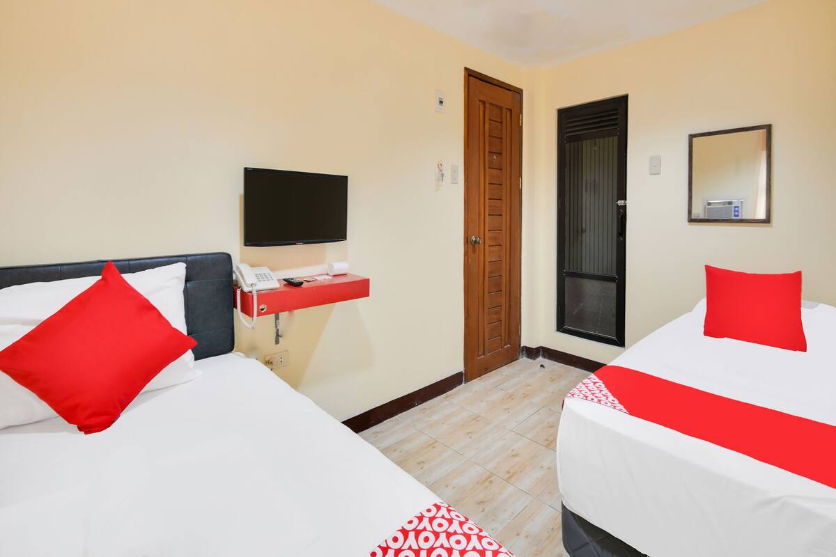 Une chambre d’hôtel avec deux lits, une télévision, un téléphone et un miroir.