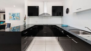 Een moderne keuken met zwarte kastjes, een roestvrijstalen spoelbak en een centraal eiland.