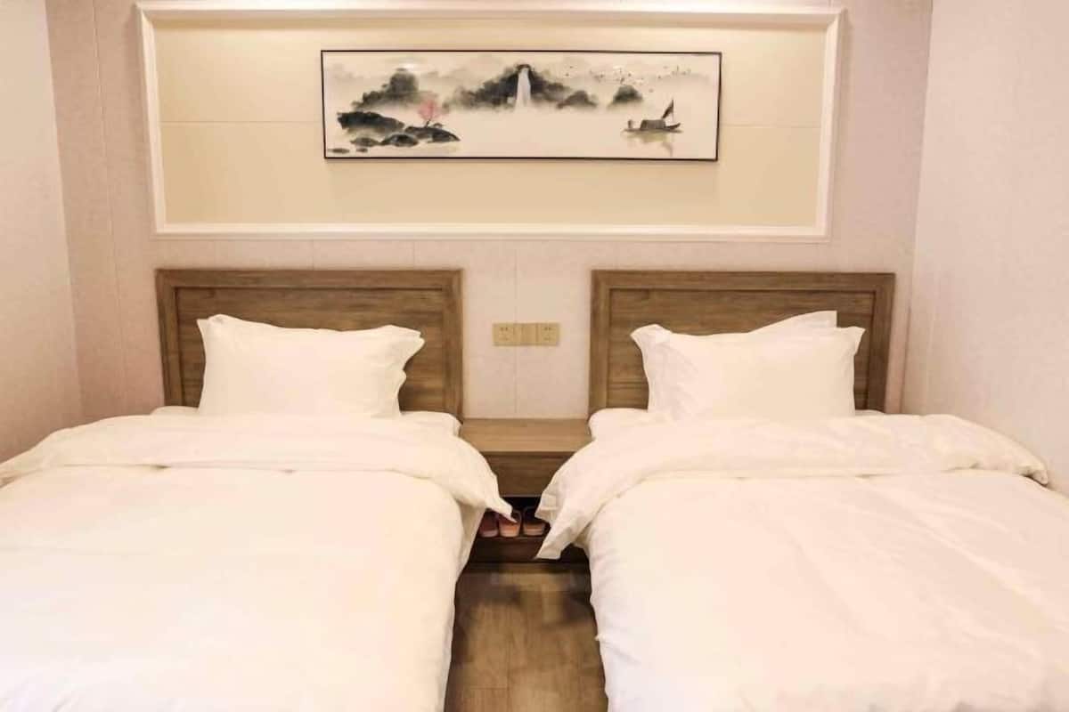 A hotel room with two beds, a wooden headboard, and a framed artwork above the beds.