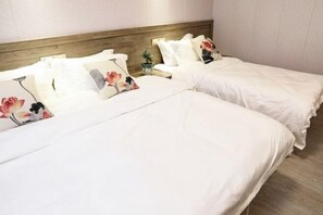 Une chambre d’hôtel avec deux lits, chacun doté de draps blancs et d’oreillers à motifs floraux.